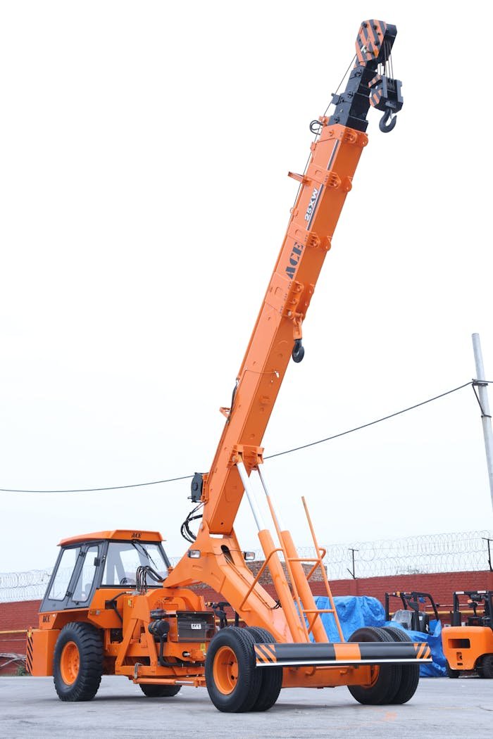 Bright orange hydraulic mobile crane in an outdoor industrial setting in India.